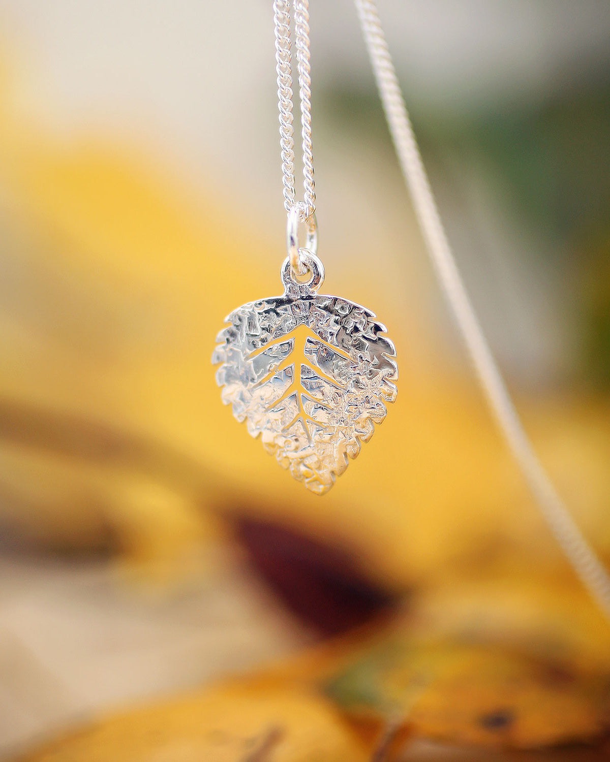 Guldviva Björk XS halsband har en tunn silverkedja. Hänget ser ut som ett björklöv.