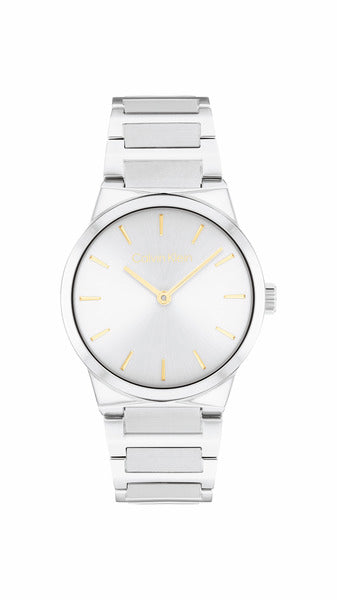 Calvin Klein Linear Elegance CK25100076 damklocka har en rund, silverfärgad urtavla med guldfärgade index och visare. Ramen, boetten och remmen är också silverfärgade.