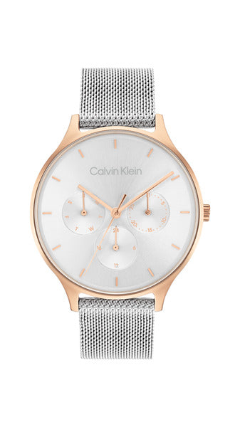 Calvin Klein Timeless Multifunction CK25200106 damklocka har en silvefärgad urtavla med datum- , veckodag- och 12/24h visning och rödguldiga index, visare och ram. Remmen är stålfärgad.