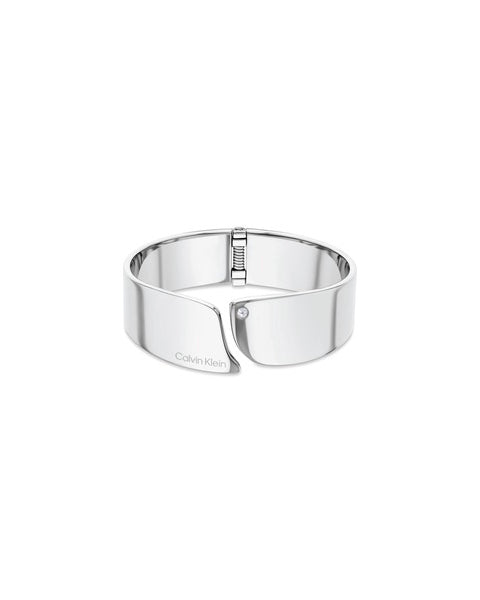 Calvin Klein Cherished CKJ35000659-armbandet är ett brett silverfärgat smycke. Den har ett praktiskt gångjärn för att göra det enkelt att sätta på smycket. Ringen är öppen mittemot gångjärnet och den öppna kanten är dekorerad med en zirkon.
