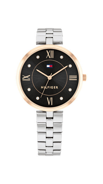 Tommy Hilfiger Ella TH1782684 damklocka har en rund, svart urtavla med roséguldfärgade index och visare. Ramen är roséguldfärgad. Boetten och remmen är silverfärgade.