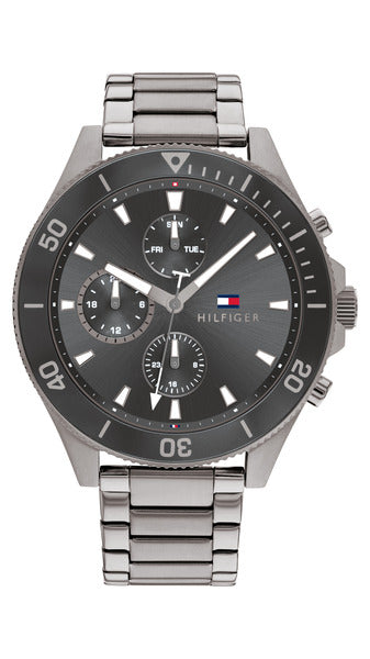 Tommy Hilfiger Larson TH1791918 herrklocka har en rund, svart urtavla med datum-, veckodag- och 12/24h-visning samt självlysande index och visare. Ramen är svart med gråa minutmarkeringar. Boetten och remmen är gråa.