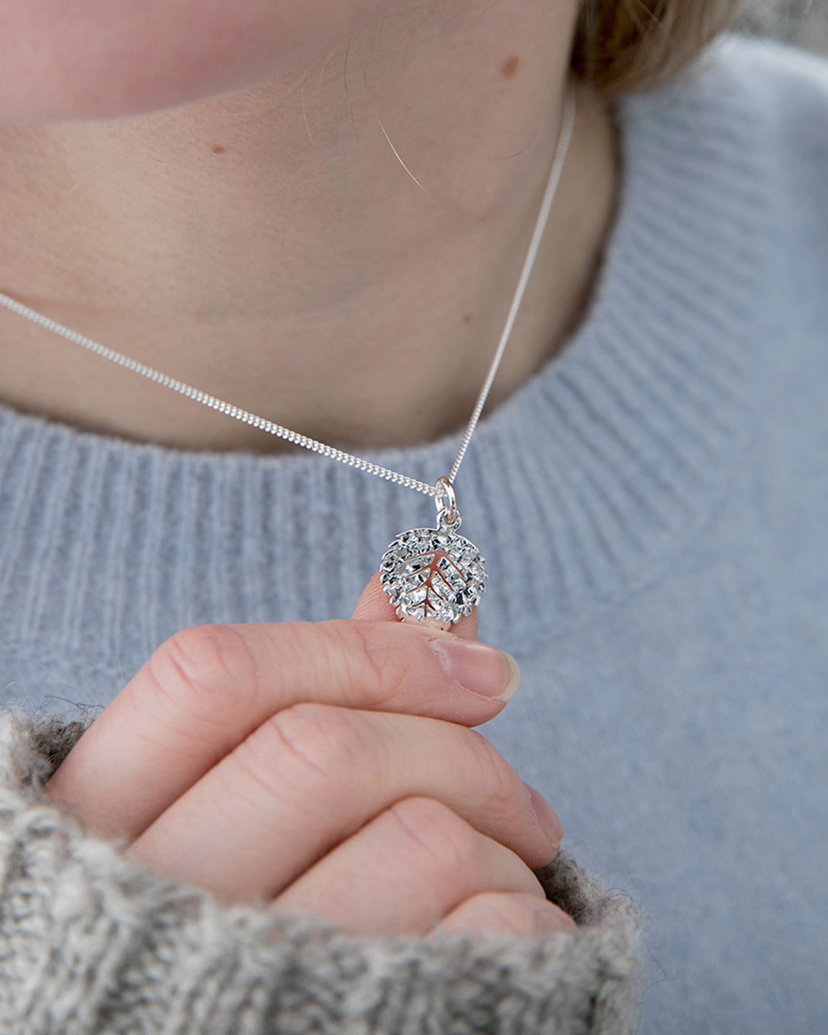 Hänget på Guldviva Björk XS-halsbandet är ungefär lika stort som en tumme.