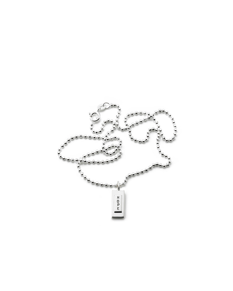 Efva Attling Little Hope 11-100-00041 halsband har en tunn silverkedja. Hänget är en silverplatta med bokstäverna H, O, P och E under varandra