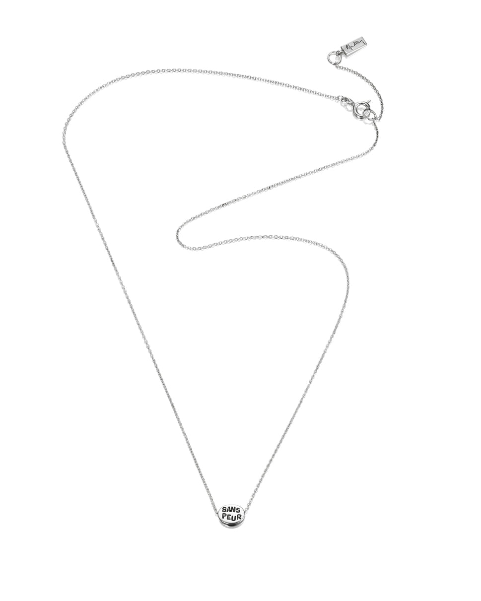 Efva Attling Mini Me Sans Peur 10-100-01282 halsband har en tunn silverkedja prydd med en liten oval plakett. På plaketten finns inskriptionen: "SANS PEUR".