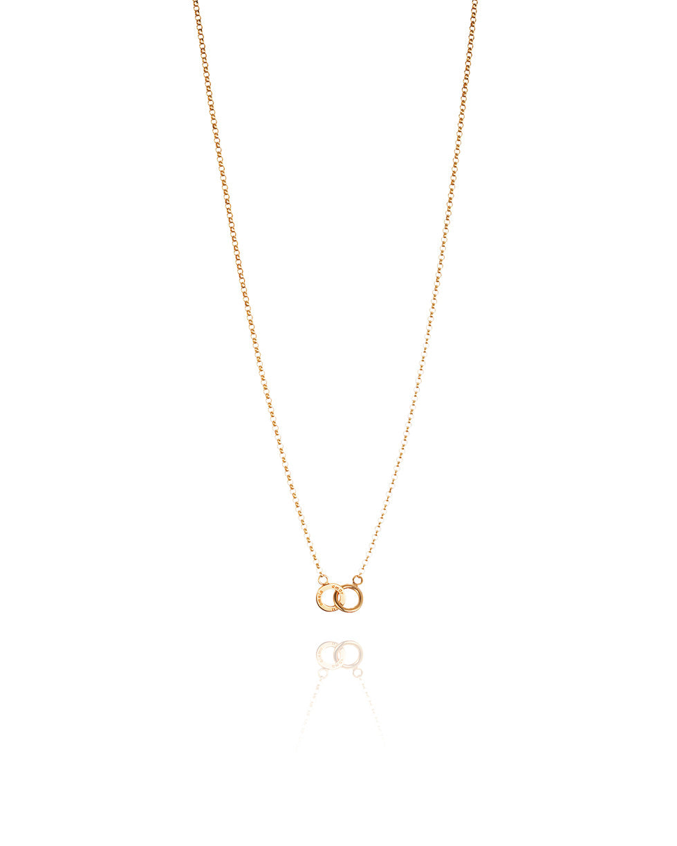 Efva Attling Mini Twosome 10-101-00565 halsband har en tunn guldkedja. Dekorationen består av två ringar som är kopplade till varandra. På en av ringarna finns inskriptionen: "AMOR VINCIT OMNIA".