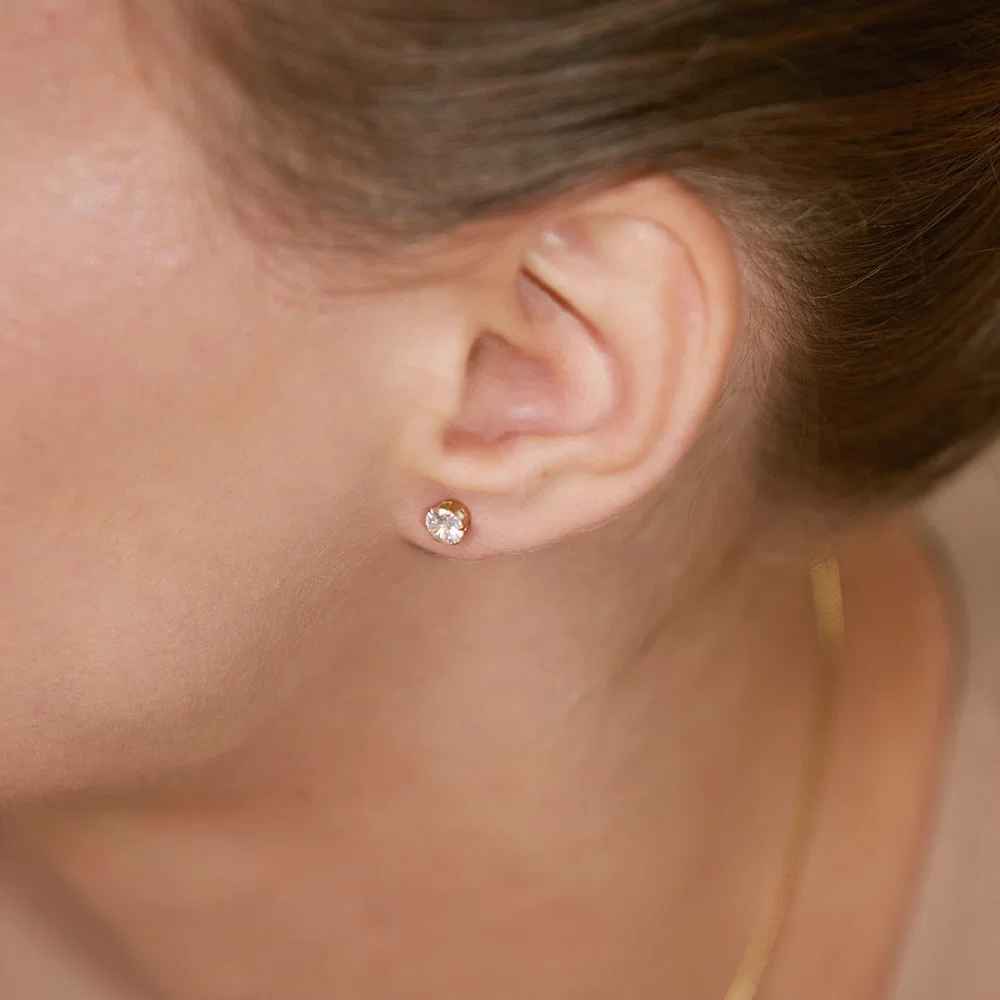 Kullattu Edblad Crown Studs Gold -zirkoniakorvakoru mallin korvassa lähikuvassa