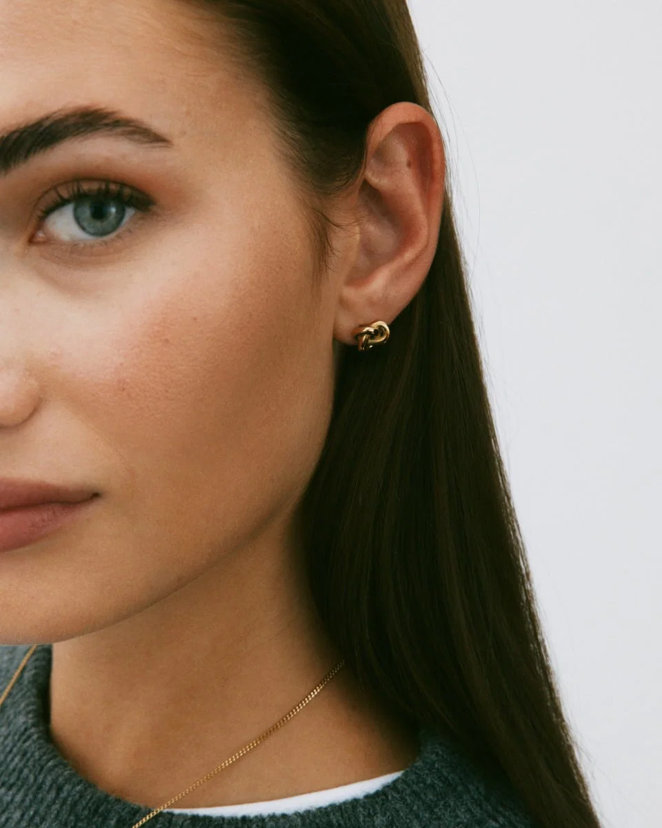 Kullatut Edblad Infinity Knot Studs S Gold -solmukorvakorut 129853 mallin korvassa
