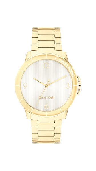 Calvin Klein Vivacious CK25100023 damklocka har en rund, silverfärgad urtavla med guldfärgade index och visare. Ramen, boetten och remmen är guldfärgade.