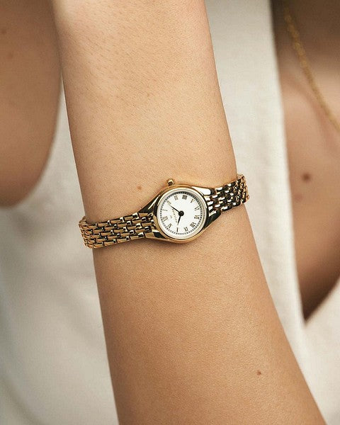 Stilfull livsstilsbild på en guldfärgad Mockberg Heritage KDBL-klocka på en kvinnas handled, som framhäver klockans nätta siluett och smyckesliknande design.