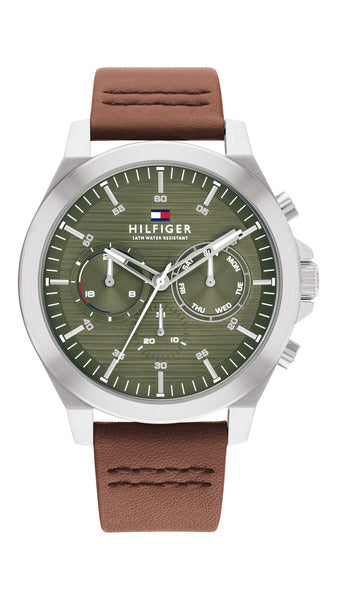 Tommy Hilfiger TH1710522 herrklocka har en rund, armé grön urtavla med datum-, veckodag- och 12/24h-visning samt silverfärgade index och visare. Ramen och boetten är silverfärgade. Remmen är en brun läderrem med bruna sömmar.