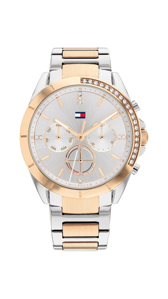 Tommy Hilfiger Kennedy TH1782387 damklocka har en rund, silverfärgad urtavla med datum-, veckodag- och 12/24h-visning samt roséguldfärgade index och visare. Ramen är också roséguldfärgad. Boetten och remmen är silverfärgade med roséguldfärgade detaljer. Ramen och index är dekorerad med smyckestenar.