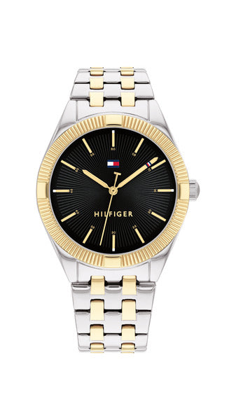 Tommy Hilfiger Rachel TH1782549 damklocka har en rund, svart urtavla med guldfärgade index och visare. Ramen är guldfärgad. Boetten och remmen är silverfärgade, och remmen har guldfärgade detaljer.
