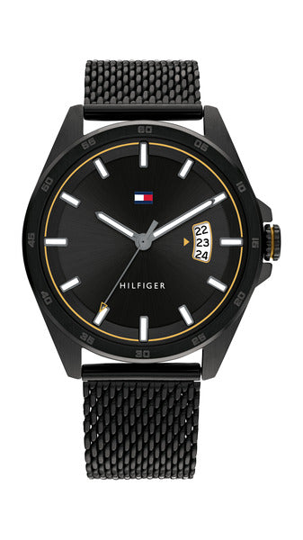 Tommy Hilfiger Carter TH1791913 herrklocka har en rund, svart urtavla med datumvisning, självlysande index och visare och en guldfärgad kant. Ramen är svart med gråa minutmarkeringar. Boetten och remmen är också svarta.